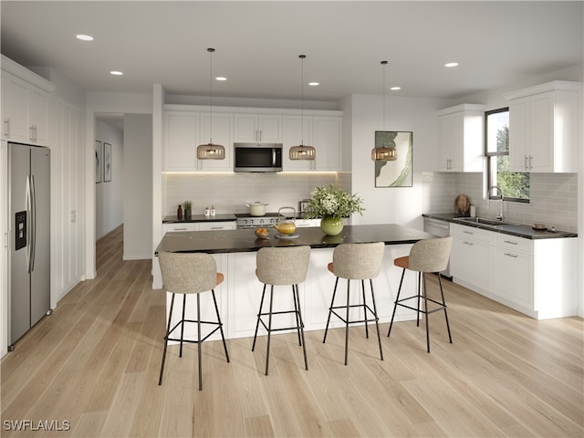 kitchen featuring tasteful backsplash, stainless steel appliances, pendant lighting, a kitchen island, and light wood-type flooring