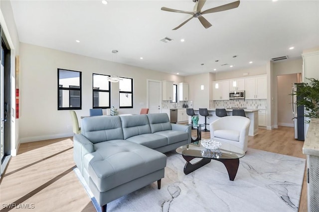 living room with recessed lighting, visible vents, and light wood-style flooring