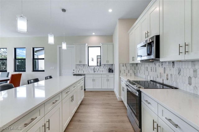 kitchen featuring appliances with stainless steel finishes, white cabinets, hanging light fixtures, and light countertops