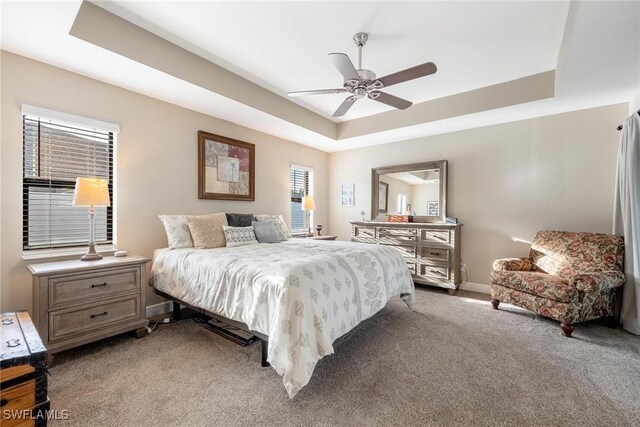 bedroom with carpet floors, ceiling fan, and a raised ceiling