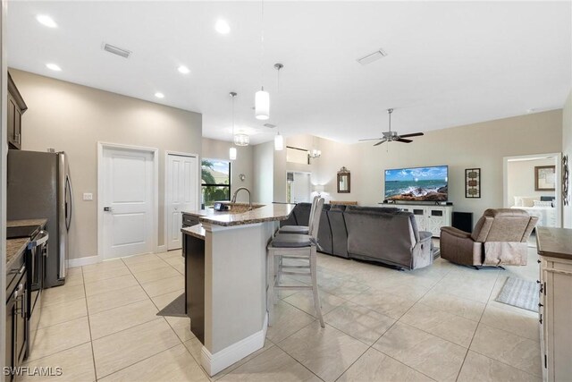 kitchen featuring a breakfast bar, pendant lighting, light tile patterned floors, an island with sink, and ceiling fan