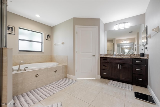 bathroom featuring tiled tub, vanity, and tile patterned floors