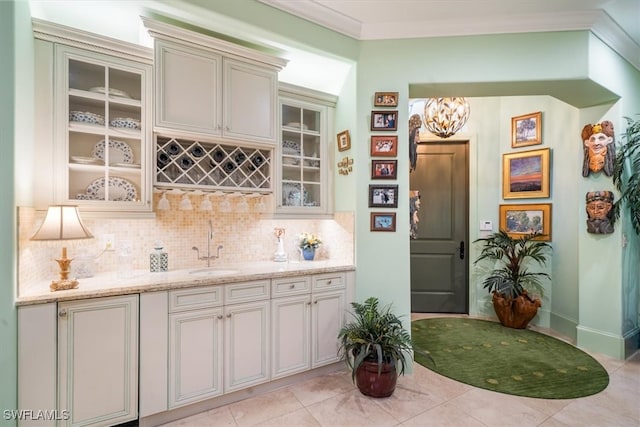 kitchen featuring backsplash, ornamental molding, sink, and light tile patterned floors