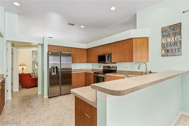 kitchen with appliances with stainless steel finishes, kitchen peninsula, sink, and light tile patterned flooring