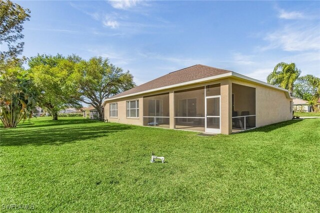 rear view of house with a lawn and a sunroom