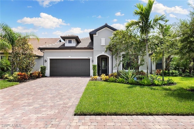 mediterranean / spanish-style house with decorative driveway, stucco siding, an attached garage, a tiled roof, and a front lawn