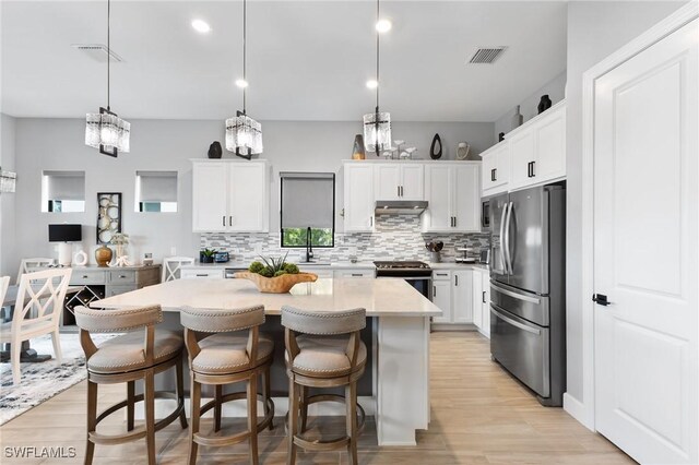 kitchen featuring white cabinetry, hanging light fixtures, a center island, and appliances with stainless steel finishes