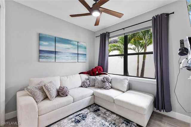 living room with a ceiling fan, baseboards, and wood finished floors