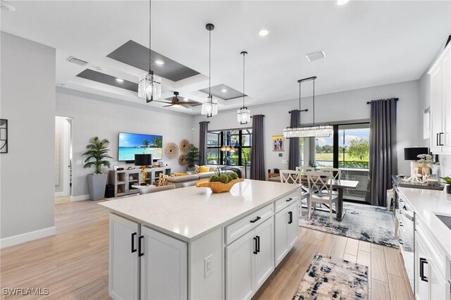 kitchen featuring a center island, white cabinets, light hardwood / wood-style floors, and decorative light fixtures