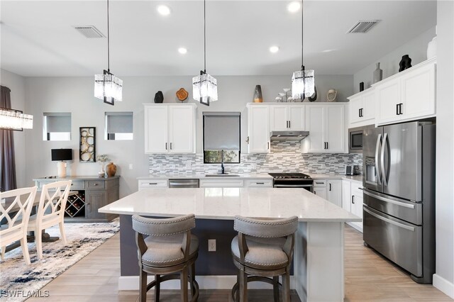 2740 Amaranda Ct, Naples, FL 34114 - kitchen with visible vents, stainless steel appliances, under cabinet range hood, an inviting chandelier, and a center island