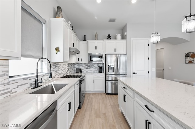 2740 Amaranda Ct, Naples, FL 34114 - kitchen with white cabinets, stainless steel appliances, under cabinet range hood, a sink, and backsplash