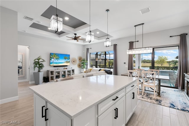 2740 Amaranda Ct, Naples, FL 34114 - kitchen with white cabinetry, a center island, light wood-type flooring, ceiling fan with notable chandelier, and visible vents
