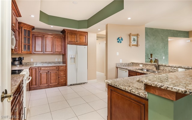 kitchen featuring light tile patterned flooring, sink, light stone countertops, white appliances, and a raised ceiling