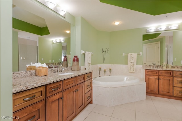 bathroom featuring a relaxing tiled tub, tile patterned floors, and vanity