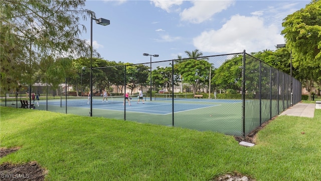 view of tennis court featuring a yard