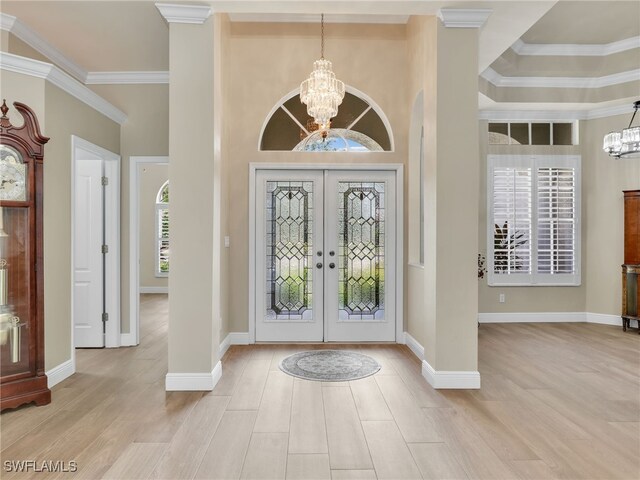 entryway featuring a high ceiling, a notable chandelier, crown molding, and french doors