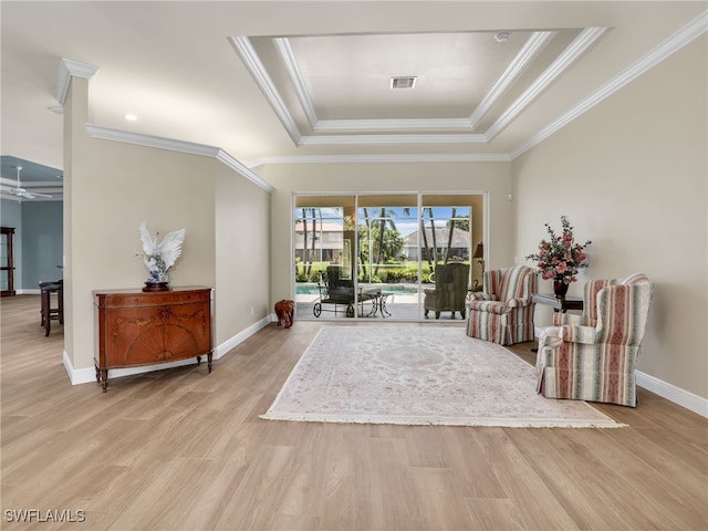 sitting room featuring light wood-type flooring, crown molding, and a tray ceiling