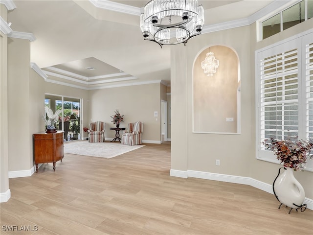 entrance foyer featuring a notable chandelier, a raised ceiling, light hardwood / wood-style floors, and ornamental molding