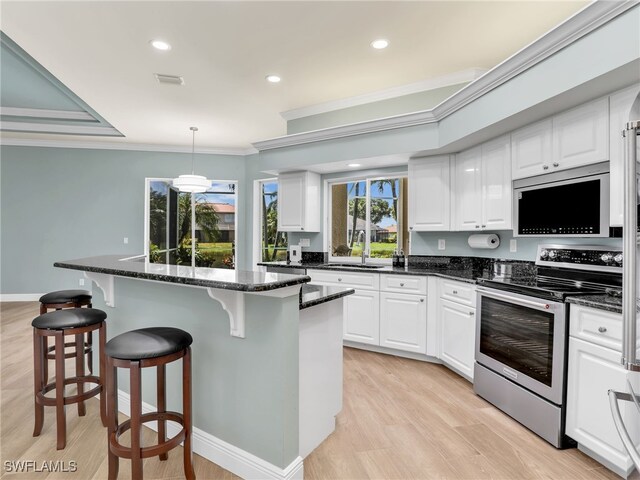 kitchen with dark stone countertops, white cabinetry, appliances with stainless steel finishes, and light hardwood / wood-style floors