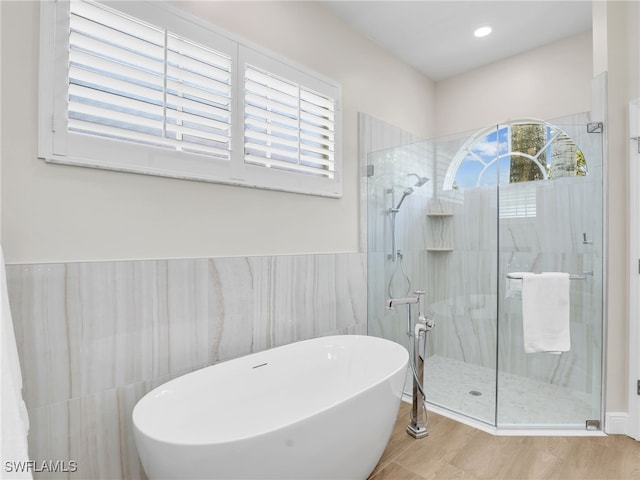 bathroom with plus walk in shower, tile walls, and hardwood / wood-style floors