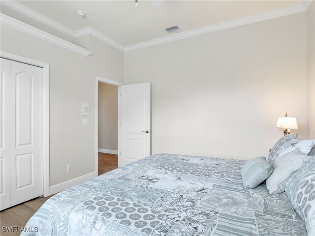 bedroom featuring a closet, ornamental molding, and wood-type flooring