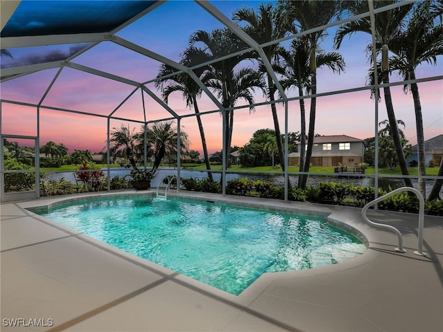 pool at dusk with a patio area and a lanai