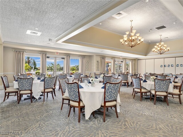 carpeted dining room featuring a notable chandelier, a textured ceiling, a tray ceiling, and ornamental molding