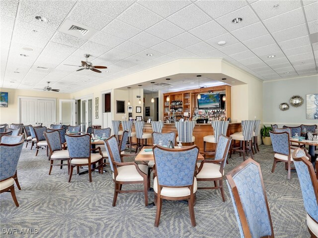 dining room with ceiling fan, a drop ceiling, and light carpet