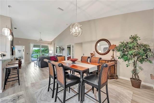 dining space featuring light wood-type flooring, high vaulted ceiling, and ceiling fan with notable chandelier