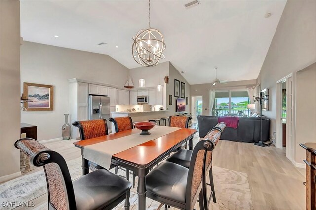 dining room featuring ceiling fan with notable chandelier, light wood-type flooring, and high vaulted ceiling