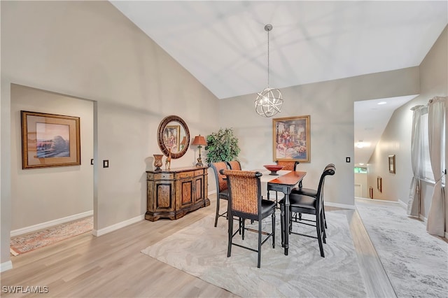 dining space with a notable chandelier, vaulted ceiling, and light hardwood / wood-style floors