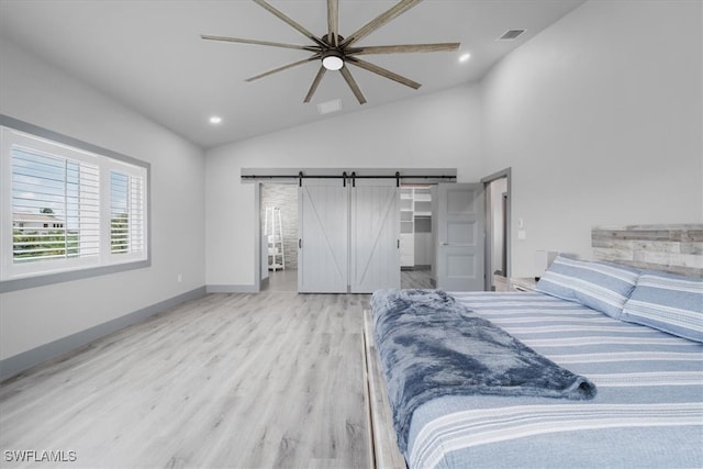 bedroom with a barn door, ceiling fan, vaulted ceiling, and light wood-type flooring