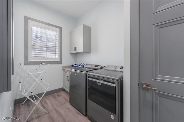 washroom featuring cabinets, light hardwood / wood-style flooring, and washer and clothes dryer