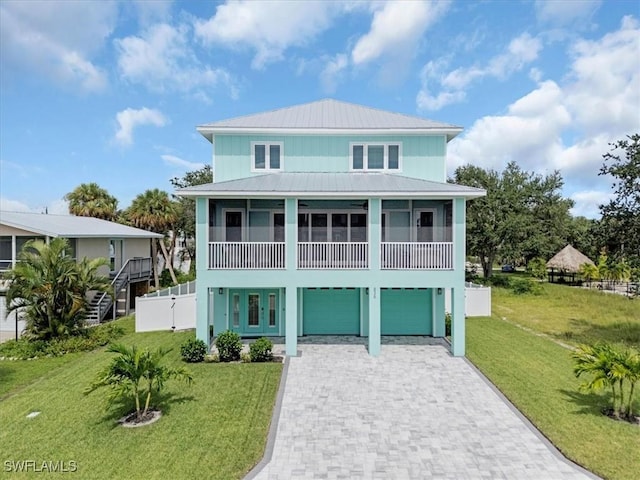 coastal inspired home featuring a garage and a front lawn