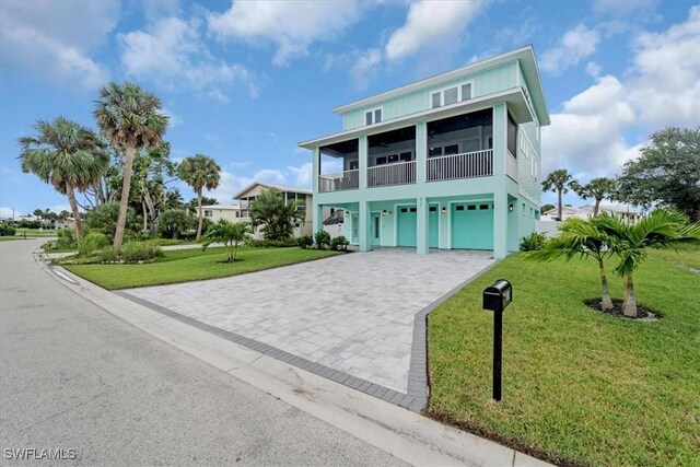 coastal inspired home featuring a balcony, a front yard, and a garage