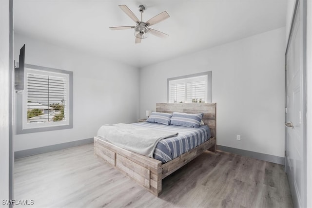 bedroom with multiple windows, ceiling fan, and hardwood / wood-style flooring