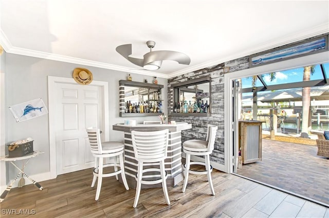 unfurnished dining area with ornamental molding, wood-type flooring, and bar