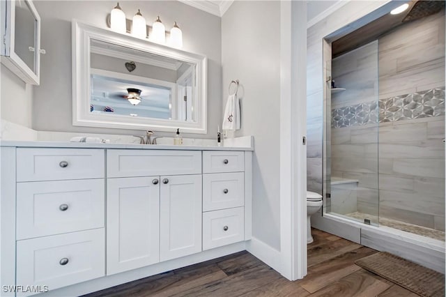 bathroom with toilet, an enclosed shower, ornamental molding, vanity, and hardwood / wood-style flooring