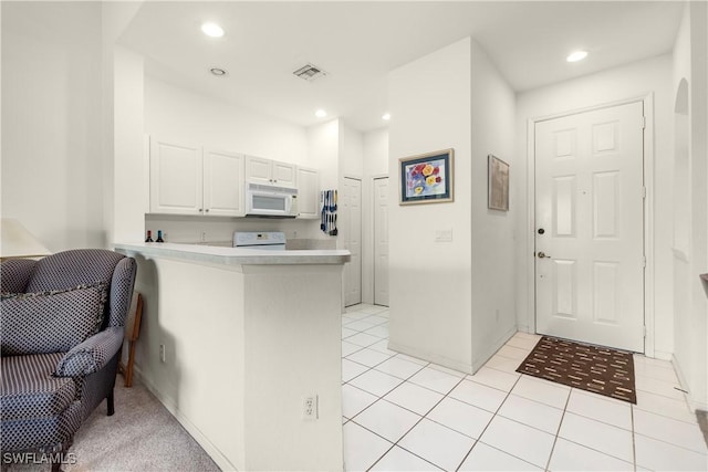 kitchen with white cabinetry, range, kitchen peninsula, and light tile patterned floors