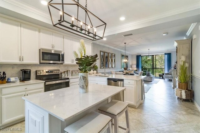 kitchen with stainless steel appliances, pendant lighting, a center island, sink, and light stone counters