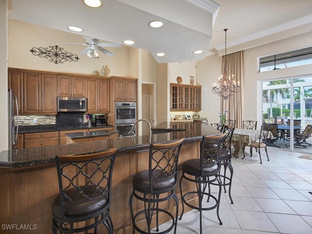 kitchen featuring ceiling fan with notable chandelier, pendant lighting, stainless steel appliances, backsplash, and light tile patterned floors