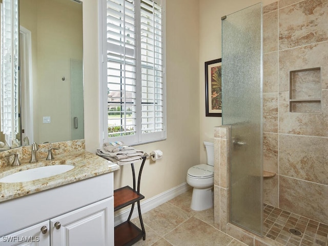 bathroom with a shower with shower door, vanity, tile patterned floors, and toilet