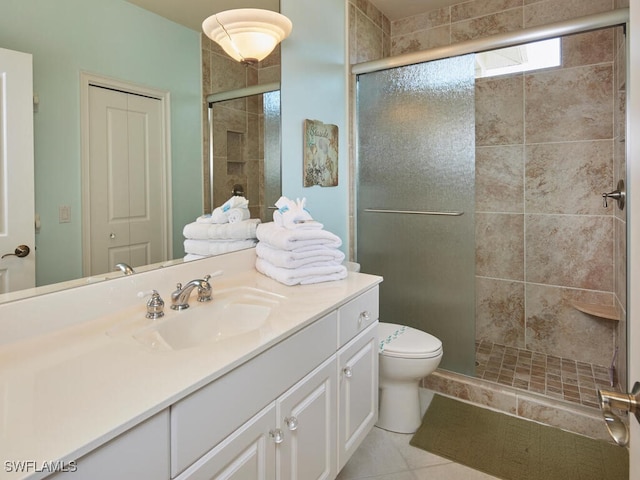 bathroom featuring toilet, tile patterned floors, vanity, and a shower with shower door