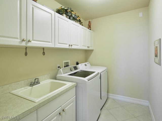 clothes washing area featuring light tile patterned floors, cabinet space, washing machine and dryer, a sink, and baseboards