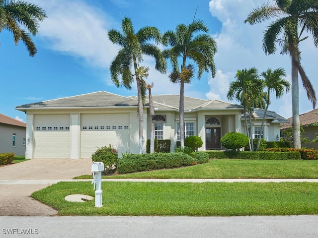 single story home featuring driveway, stucco siding, a garage, and a front yard