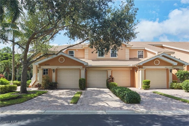 view of front of house featuring a garage, a tile roof, decorative driveway, and stucco siding