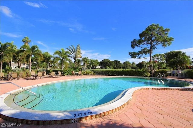 pool with a patio area and fence