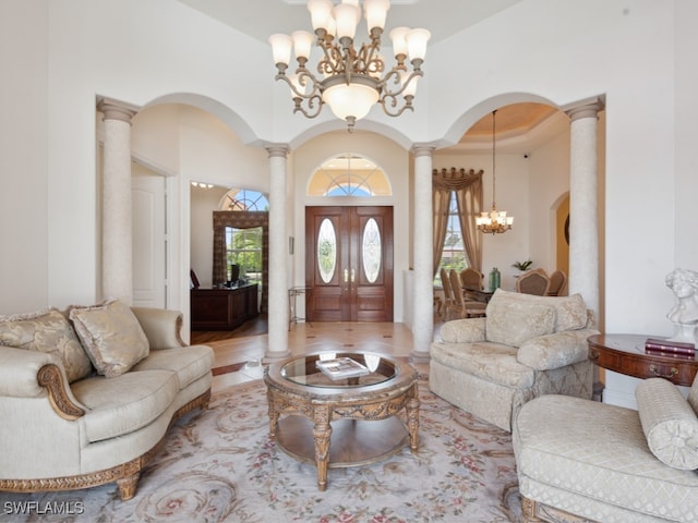 tiled living room featuring decorative columns, a towering ceiling, and a chandelier