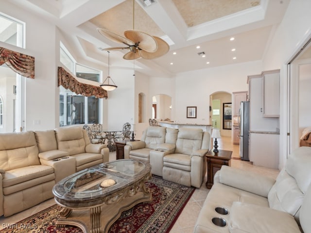 living room featuring ceiling fan, crown molding, a high ceiling, coffered ceiling, and light tile patterned floors