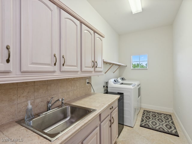 laundry area featuring light tile patterned flooring, sink, cabinets, and washer and clothes dryer